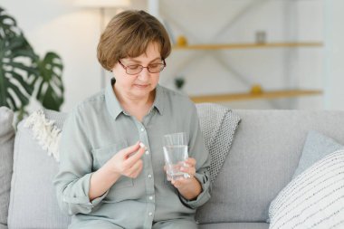 Olgun orta yaşlı kadın kıdemli holding hap ve ağrı gidermek için ağrı kesici su, tıp takviyeleri vitamin, antibiyotik ilaç, ilaç eski kişi kavramı için görünümü kapatın