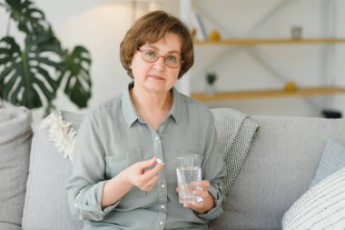 Olgun orta yaşlı kadın kıdemli holding hap ve ağrı gidermek için ağrı kesici su, tıp takviyeleri vitamin, antibiyotik ilaç, ilaç eski kişi kavramı için görünümü kapatın
