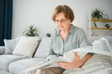 yaş ve insanlar kavramı - mutlu üst düzey kadın evde gazete okuma.