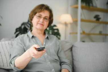 teknoloji, televizyon, yaş ve insanlar kavramı - tv izliyor ve Uzaktan kumanda evde ile kanal değiştirme mutlu kadın kıdemli.