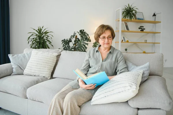 Çekici odaklı neşeli kadının portresi divanda oturmuş kitap okuyor. Ev içinde boş hayaller kuruyor.