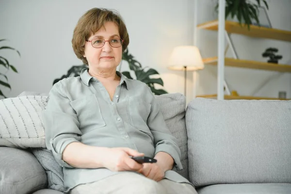 kişi, televizyon ve eğlence kavramı - gözlük evde televizyonun uzaktan kumandası ile üst düzey kadın.