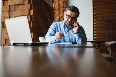 Kafede dizüstü bilgisayarda çalışan son sınıf erkek serbest yazar. uzak çalışma konsepti