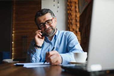 Kafede dizüstü bilgisayarda çalışan son sınıf erkek serbest yazar. uzak çalışma konsepti