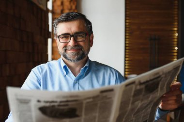 Sabahki gazete için. Ofisindeki kıdemli işadamı gazete okuyor.