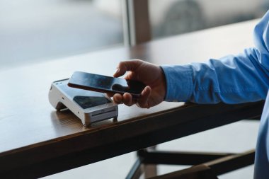 Olgun iş adamı NFC teknolojisiyle irtibatsız kredi kartıyla ödeme yapıyor.