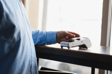 Olgun iş adamı NFC teknolojisiyle irtibatsız kredi kartıyla ödeme yapıyor.