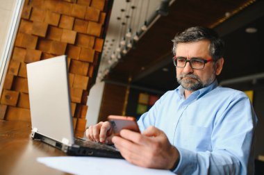 Kafede dizüstü bilgisayarda çalışan son sınıf erkek serbest yazar. uzak çalışma konsepti