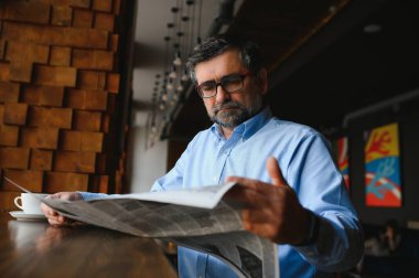 Kahve molası. Kahve içip kafe barda gazete okuyan bir adam..