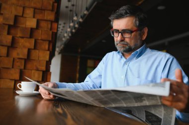 Kahve molası. Kahve içip kafe barda gazete okuyan bir adam..