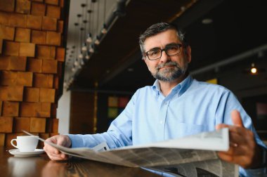 Kahve molası. Kahve içip kafe barda gazete okuyan bir adam..