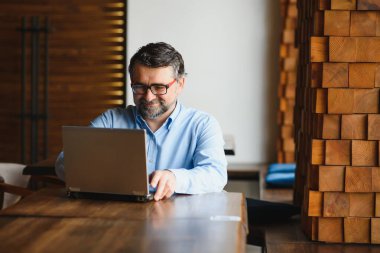 Kafede kahve içen olgun bir iş adamı. Güzel gözlükler takan, dizüstü bilgisayar kullanan, kameraya bakıp gülümseyen yakışıklı bir adamın portresi. Kahve molası.