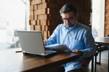 Kafede dizüstü bilgisayarda çalışan son sınıf erkek serbest yazar. uzak çalışma konsepti