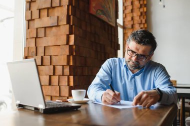 Kafede dizüstü bilgisayarda çalışan son sınıf erkek serbest yazar. uzak çalışma konsepti