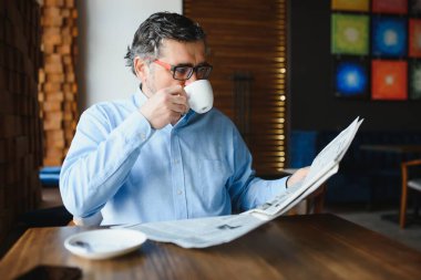 Kahve molası. Kahve içip kafe barda gazete okuyan bir adam..