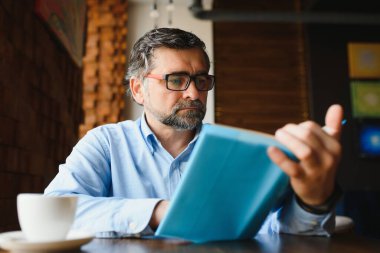 Bir kafede kitap okuyan yaşlı adam, edebi hobisi zevk.