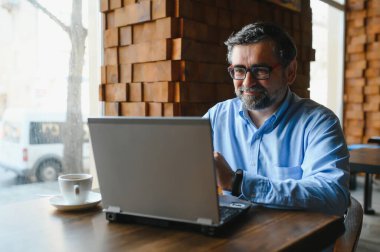 Kafede dizüstü bilgisayarda çalışan son sınıf erkek serbest yazar. uzak çalışma konsepti