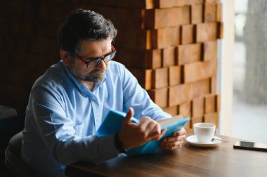 Bir kafede kitap okuyan yaşlı adam, edebi hobisi zevk.