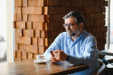 Restoranda oturup öğle yemeğini bekleyen mutlu iş adamı. Akıllı telefon kullanıyor ve biriyle konuşuyor. İş dünyası yaşlıları yaşam tarzı konsepti