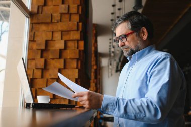 Kafede dizüstü bilgisayarda çalışan son sınıf erkek serbest yazar. uzak çalışma konsepti