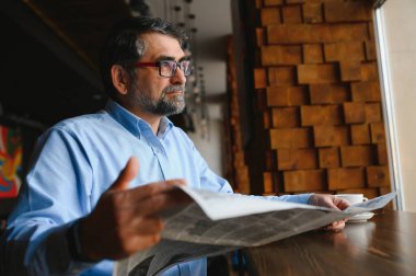 Kahve molası. Kahve içip kafe barda gazete okuyan bir adam..