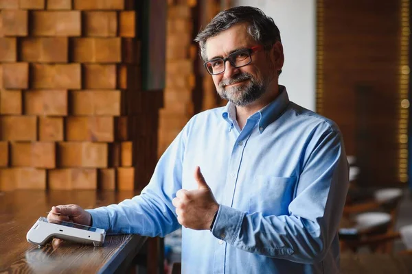 Olgun iş adamı NFC teknolojisiyle irtibatsız kredi kartıyla ödeme yapıyor.