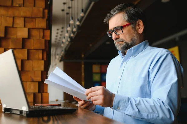 Erkek serbest yazar yeni bir iş projesi için bir kafede çalışıyor. Masadaki büyük bir pencerede oturuyor. Bir fincan kahveyle dizüstü bilgisayara bakıyor..