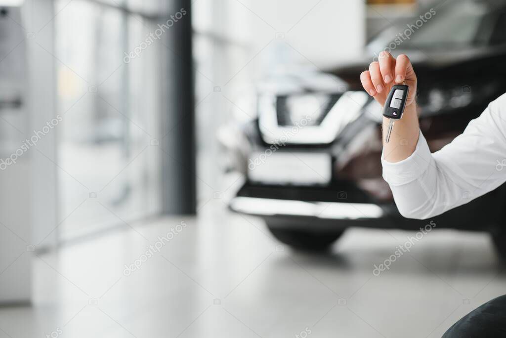 Close up of the car owner's hand holding the delivery key to buyers. Concept of selling cars and giving keys to new owners.