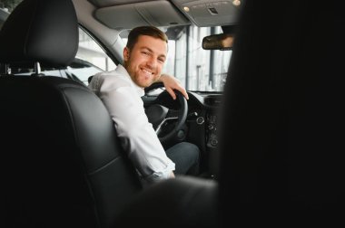 Taksi şoförü arka koltuğa dönüp müşterilerle konuşurken gülümsüyor. Başarılı bir iş adamı araba almadan önce krupiyenin arka koltuğuna bakıyor..