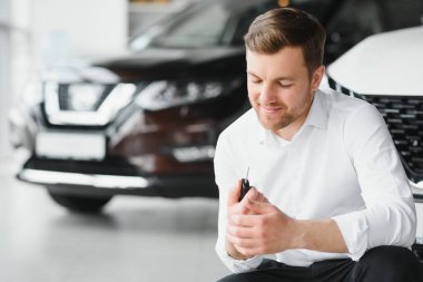 Modern avtosalon binanın önünde arabanın yanında tutan mutlu alıcı tuşları.