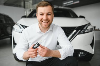 Modern avtosalon binanın önünde arabanın yanında tutan mutlu alıcı tuşları.