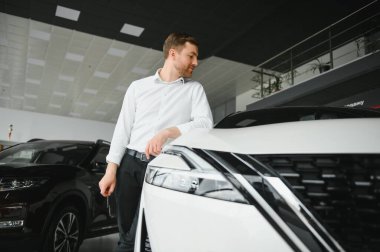 Gösteri odasındaki genç yakışıklı adam arabanın yanında duruyor..