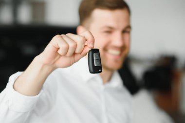 Modern avtosalon binanın önünde arabanın yanında tutan mutlu alıcı tuşları.