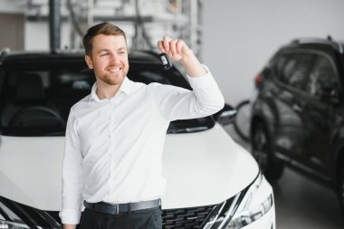 Modern avtosalon binanın önünde arabanın yanında tutan mutlu alıcı tuşları.