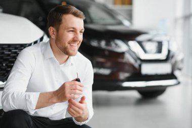 Modern avtosalon binanın önünde arabanın yanında tutan mutlu alıcı tuşları.