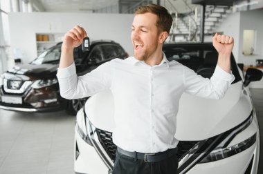 Modern avtosalon binanın önünde arabanın yanında tutan mutlu alıcı tuşları.