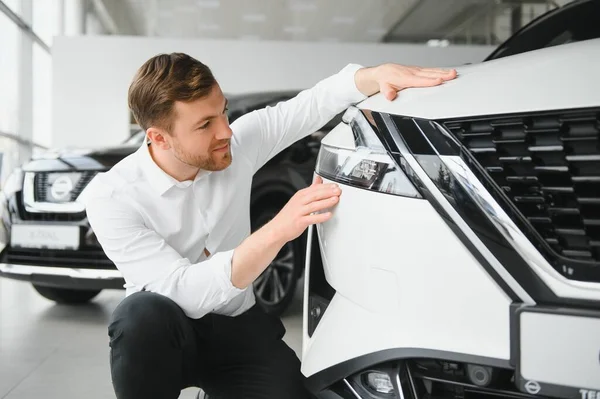 Araba galerisini ziyaret ediyorum. Yakışıklı sakallı adam yeni arabasını okşuyor ve gülümsüyor.