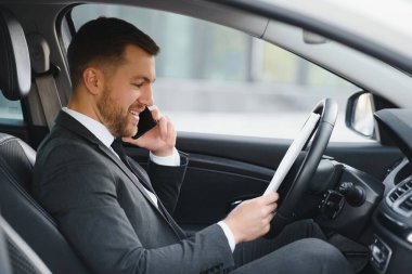 Her zaman acelen var. Takım elbiseli yakışıklı genç adam araba kullanırken gülümsüyor.