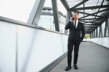 Kendinden emin genç işadamı şehirde cep telefonu kullanıyor