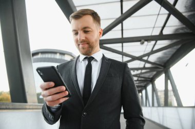Kendinden emin genç işadamı şehirde cep telefonu kullanıyor