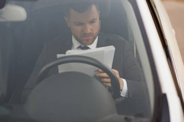 Her zaman acelen var. Takım elbiseli yakışıklı genç adam araba kullanırken gülümsüyor.