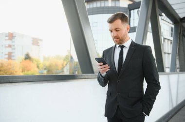 Kendinden emin genç işadamı şehirde cep telefonu kullanıyor