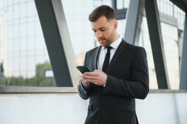 Kendinden emin genç işadamı şehirde cep telefonu kullanıyor