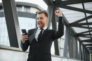 Kendinden emin genç işadamı şehirde cep telefonu kullanıyor