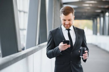 Şehirde cep telefonu kullanan ve kahve içen kendine güvenen genç bir işadamı..