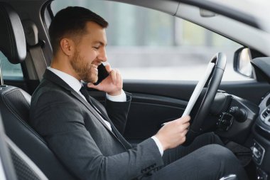 Her zaman acelen var. Takım elbiseli yakışıklı genç adam araba kullanırken gülümsüyor.