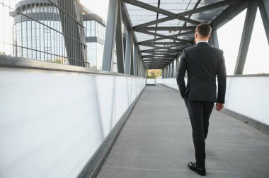 Ofisin yanındaki borsacı. Başarılı ve yetenekli takım elbiseli bir iş adamı önüne bakıp arka planda duran somut adımlara bakar.