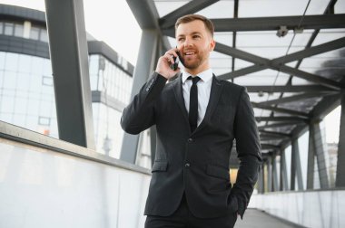 Kendinden emin genç işadamı şehirde cep telefonu kullanıyor