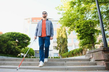 sopa tutan kaldırımda yürüyen kör adam.