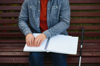 Kör adam parkta bankta kitap okuyor..